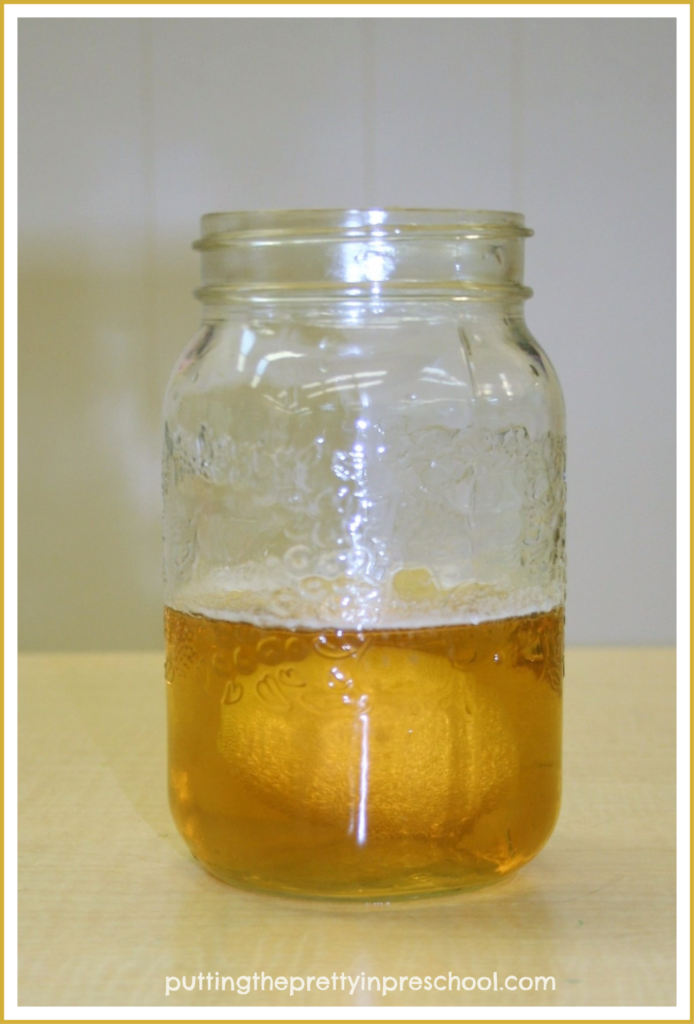 A boiled egg immersed in a jar half-filled with cider vinegar.