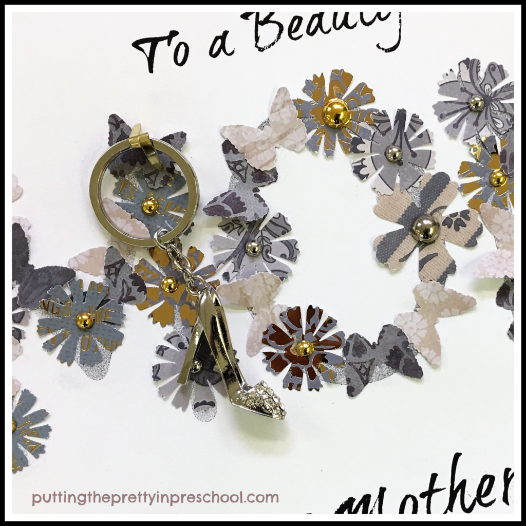 A pretty key chain gift fastened to the word "mom" in a Mother's Day paper collage craft. This art activity is suitable for all ages.