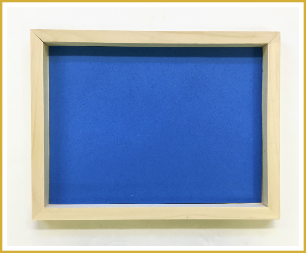 A wooden canvas paint board with a blue piece of fade-resistant paper tucked inside.