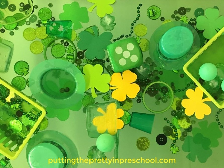 Water table filled with green and gold St. Patrick's Day-themed loose parts.