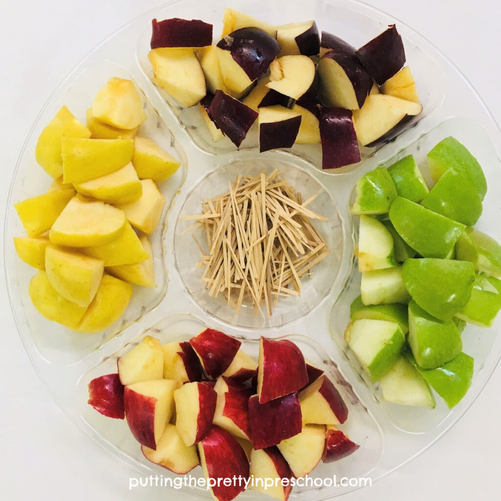 Invitation to build an apple chunk and toothpick sculpture. Green, red, and yellow apples are used in this construction challenge.