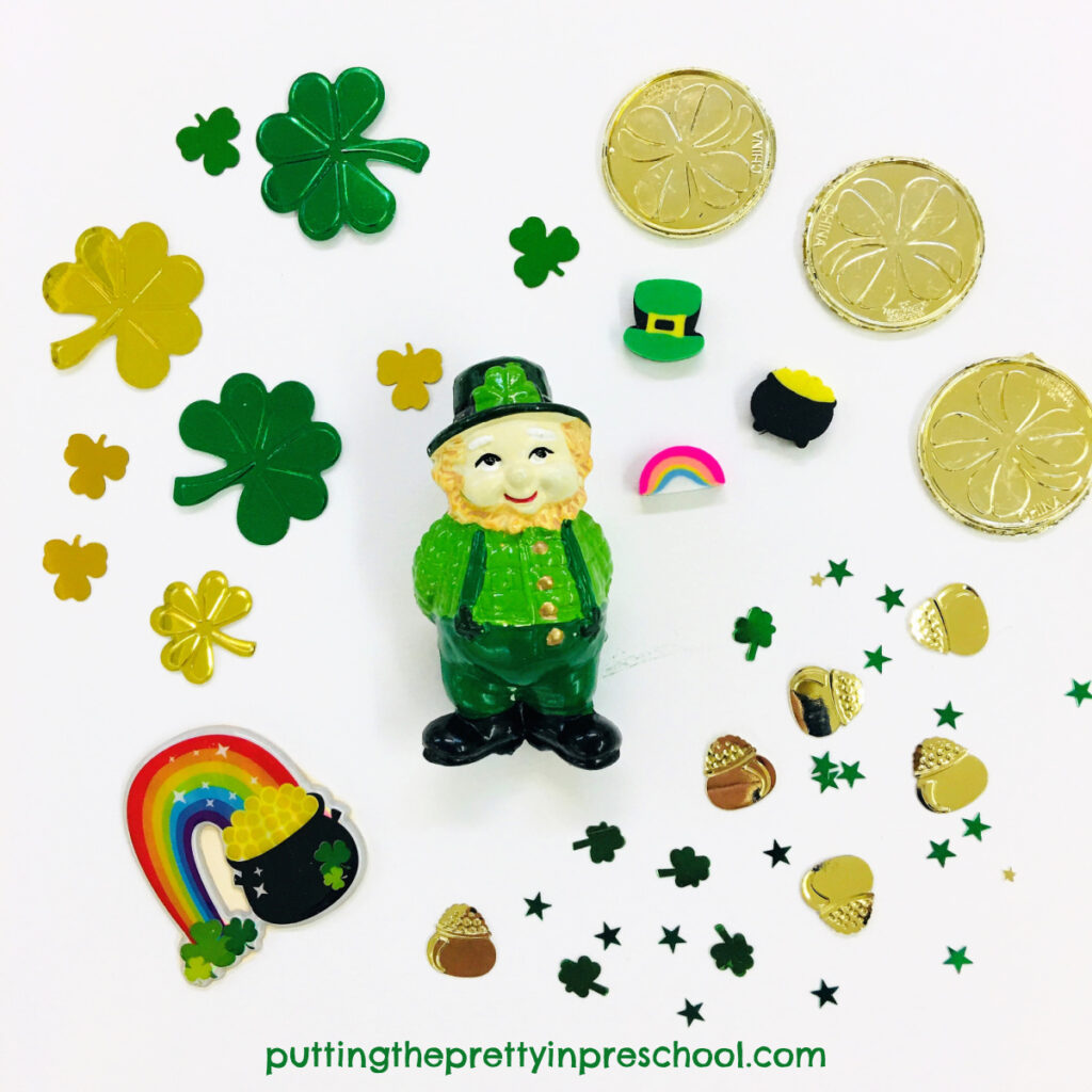 St. Patrick's Day loose parts with gold coins, foil shamrocks, rainbows, pots of gold, and a leprechaun.