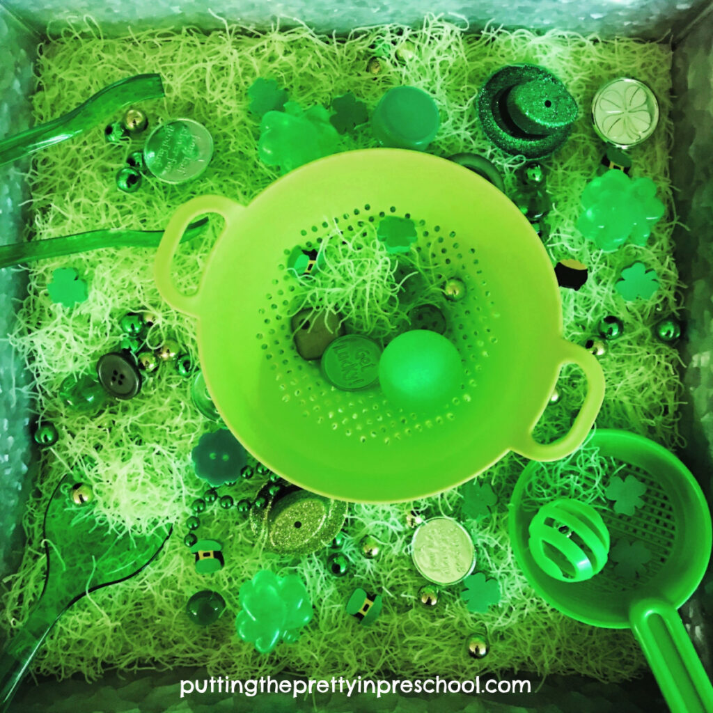 St. Patrick's Day rice noodle tray with leprechaun hats, green sieves, utensils and loose parts.
