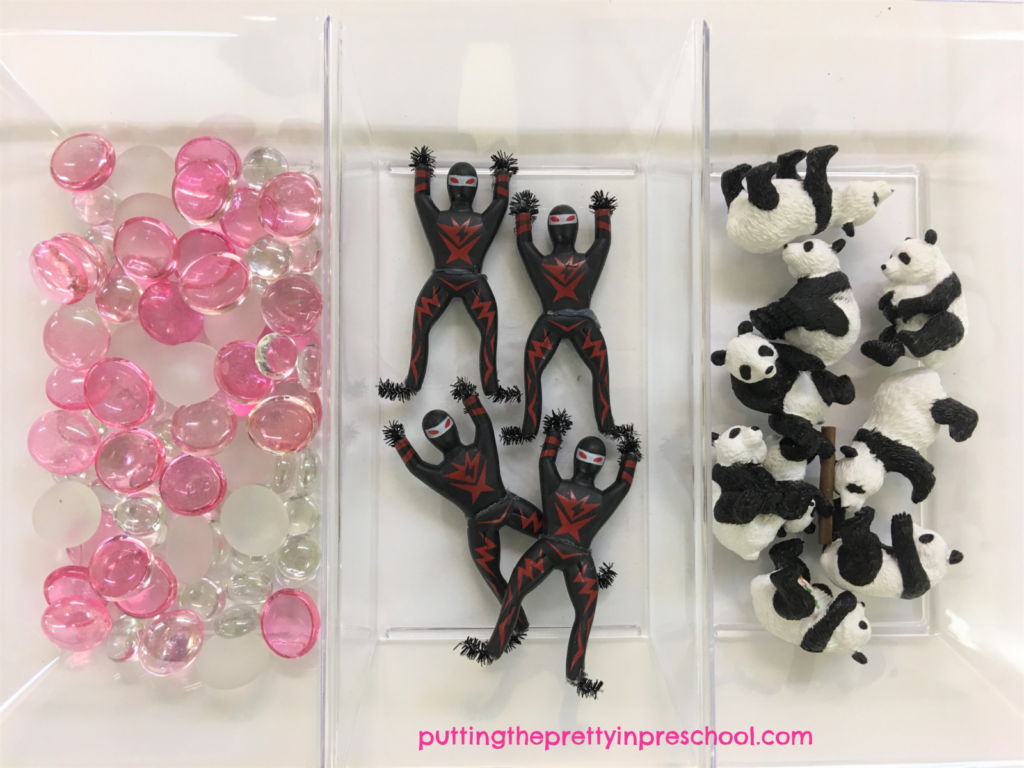 Ninja-themed loose parts tray with panda bears, ninja figurines, and pink and white gems.