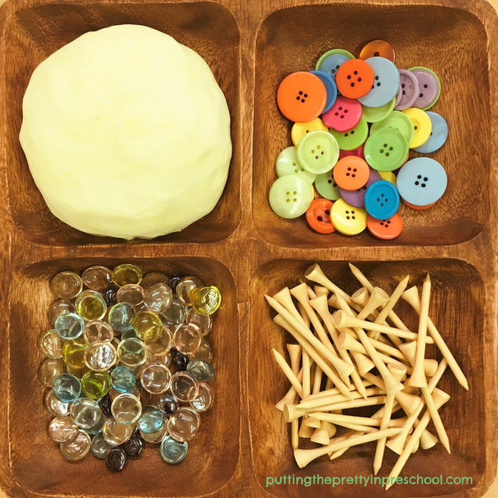 Invitation to play with coconut-scented, two-ingredient playdough and buttons, gems, and golf tees.