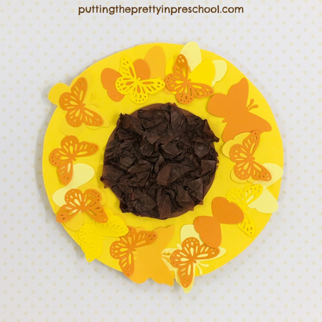 A sunflower head with a scrunched tissue center surrounded by paper butterflies.