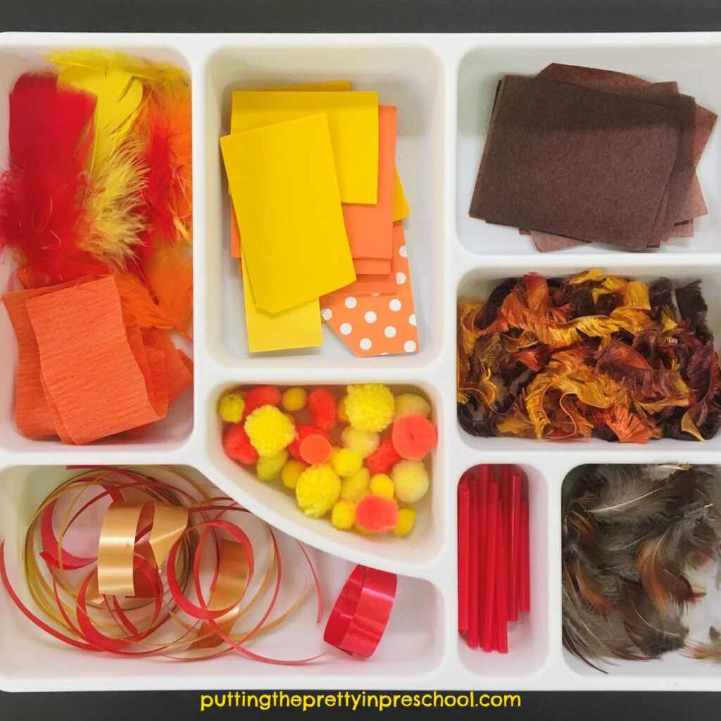 Fall scissor skills tray with red, yellow, orange, and brown craft supplies. Invitation to cut materials for collage or a sensory base.