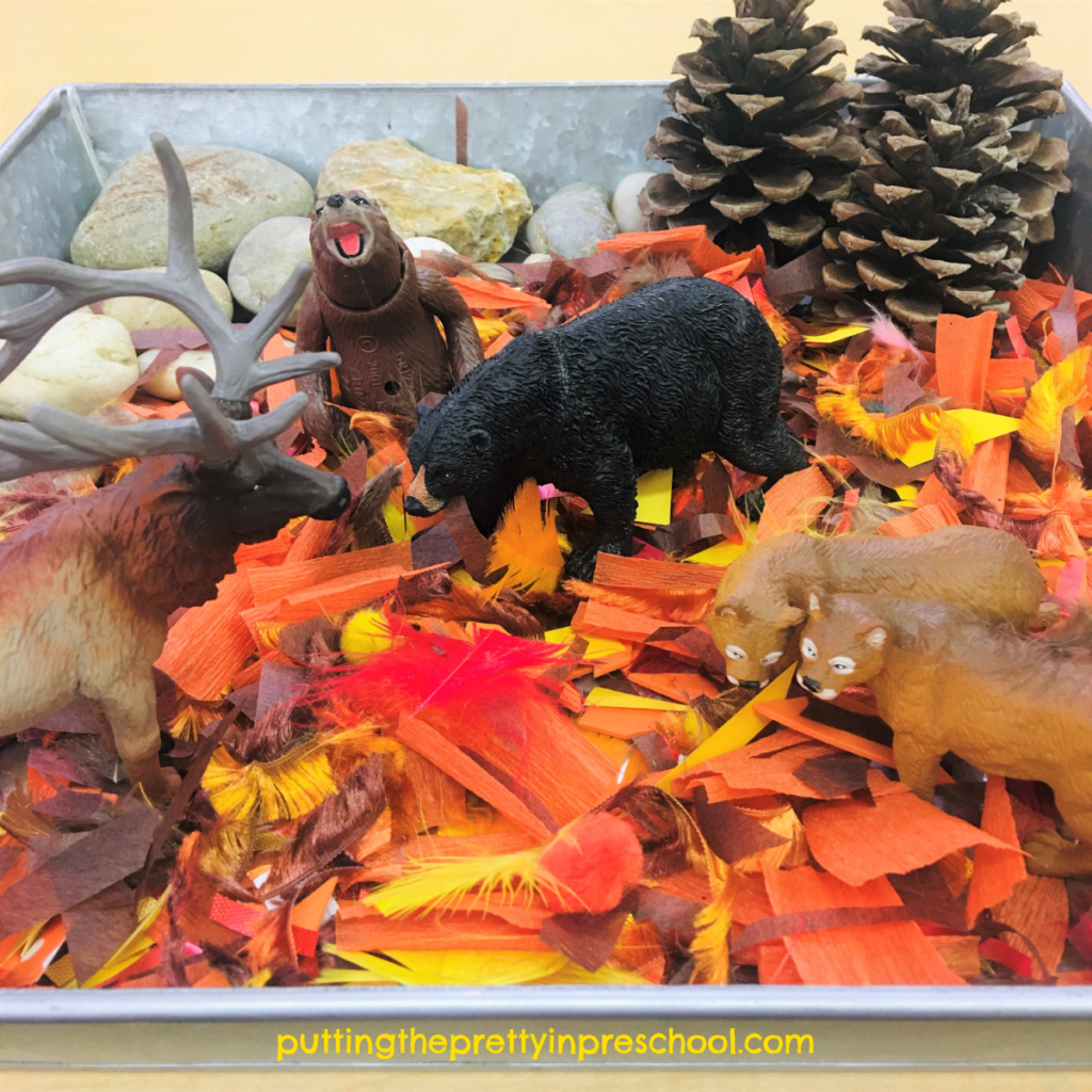 Forest sensory tray with a craft supply base. Rocks, pine cone trees, and forest animals complete the tray.