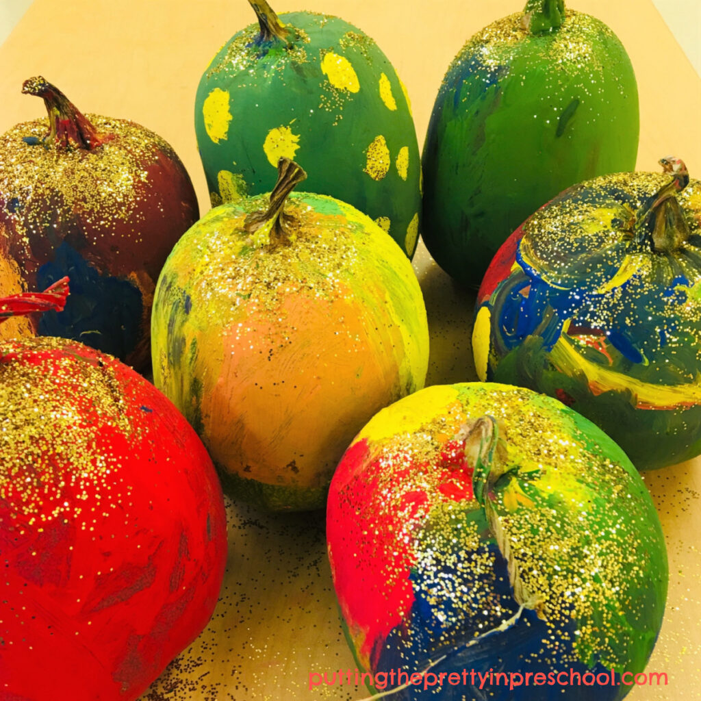 Tempera painted pumpkins sprinkled with gold glitter.