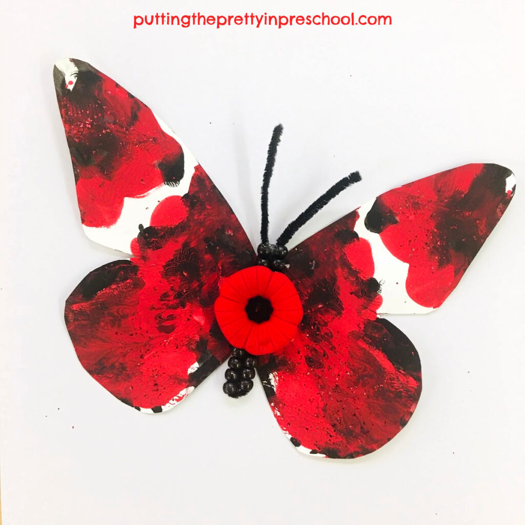Squish painted butterfly with a poppy and beadwork for Remembrance Day.