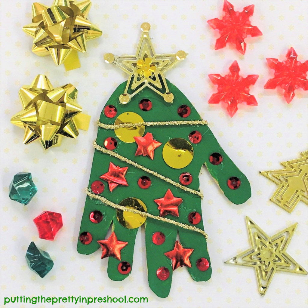 Christmas tree handprint craft. Metallic balls, sequins, stars, and garland decorate the tree.