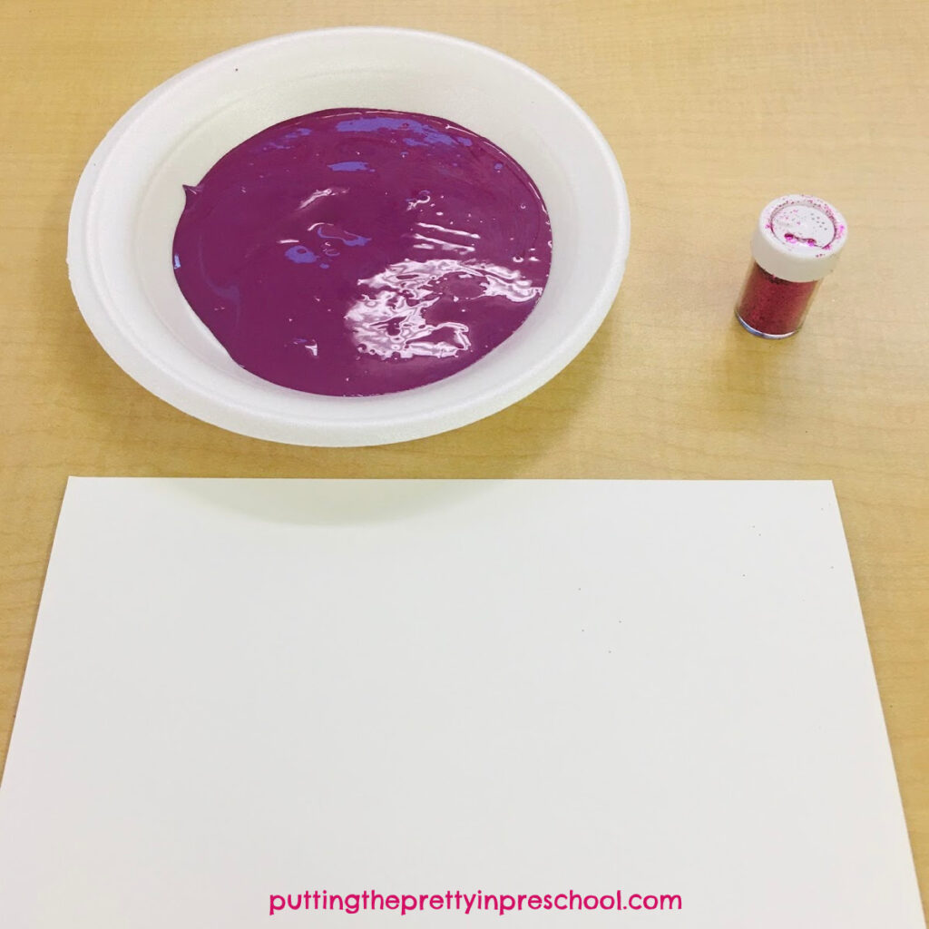 Invitation to make a magenta and pink glitter handprint.
