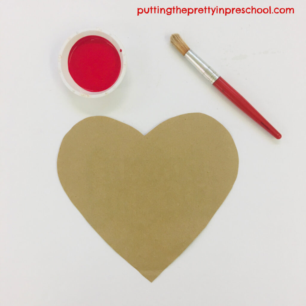 Invitation to paint a hand to make a print on a paper bag heart.