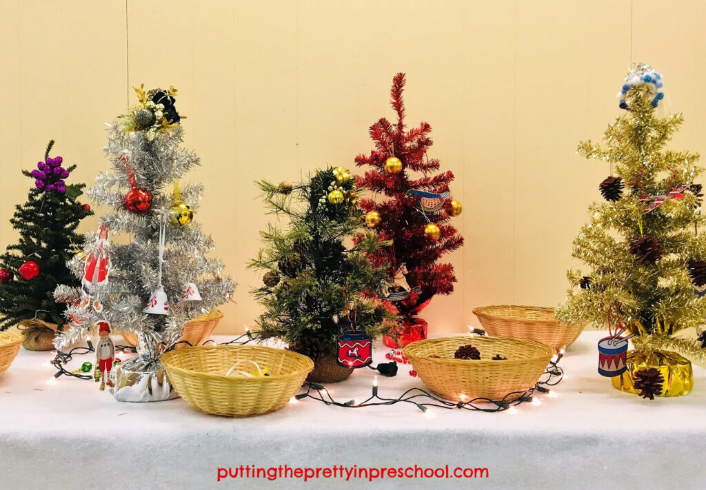 Mini Christmas trees set up for early learners to decorate with child-friendly decorations.