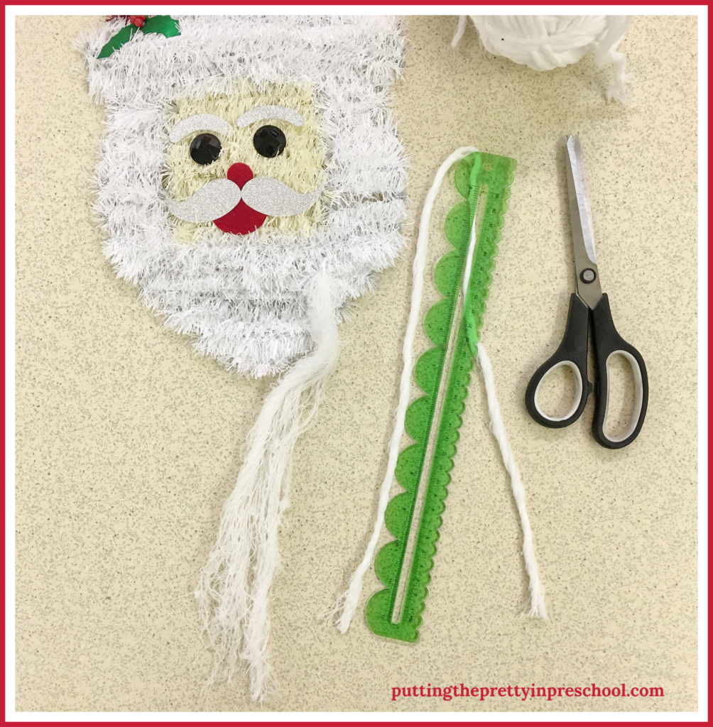 Cut strips of yarn in 60-cm/24-inch sections to string through Santa head wall decor. A scissor practice activity for young children.