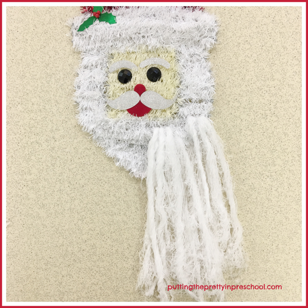 Repurpose Santa Head Wall Decor as a scissor skill activity. String white yarn to enhance Santa's beard and prepare it for cutting.