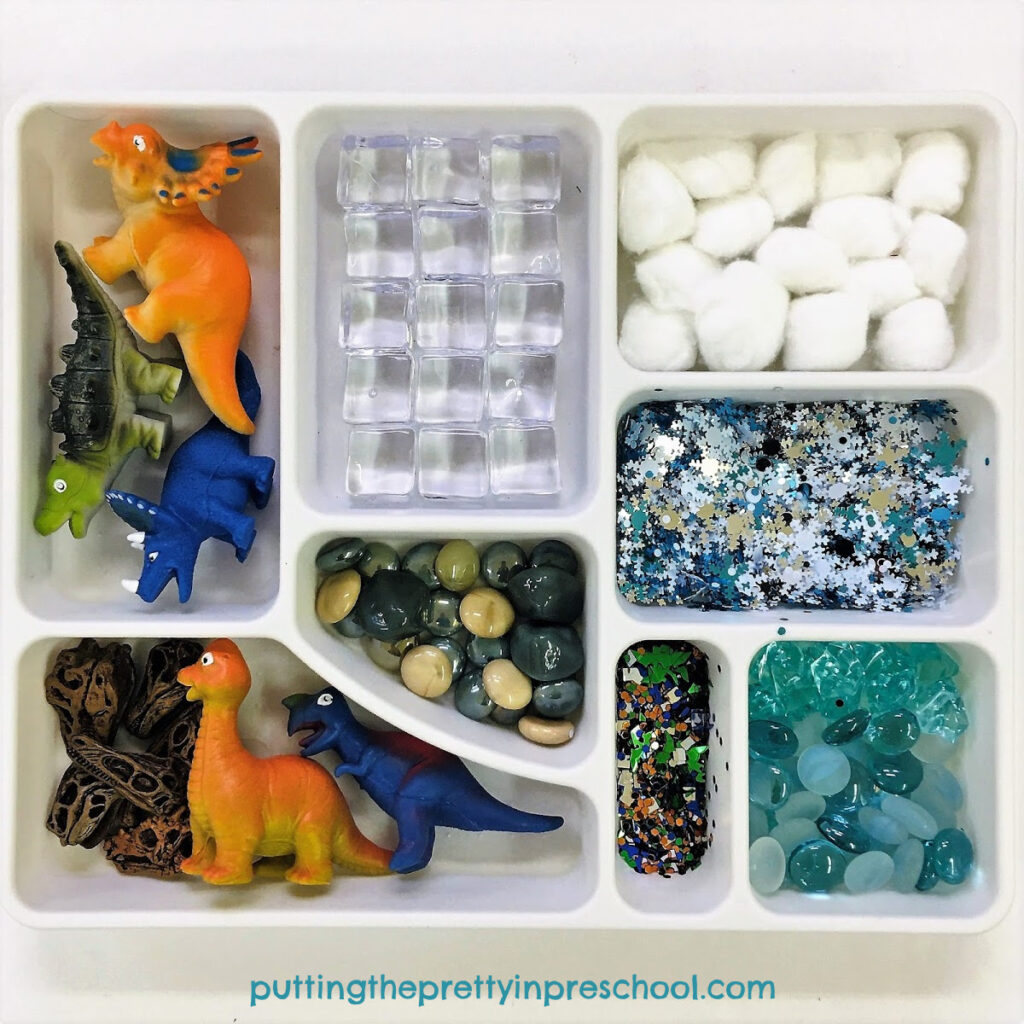 Loose parts tray featuring dinosaurs and winter-themed loose parts, perfect for exploring a polar dinosaur theme.