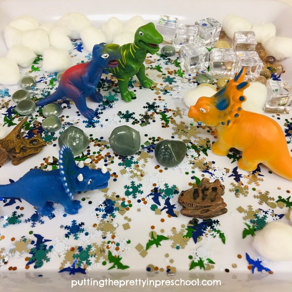 Polar dinosaur sensory play with dinosaurs and winter-themed loose parts.