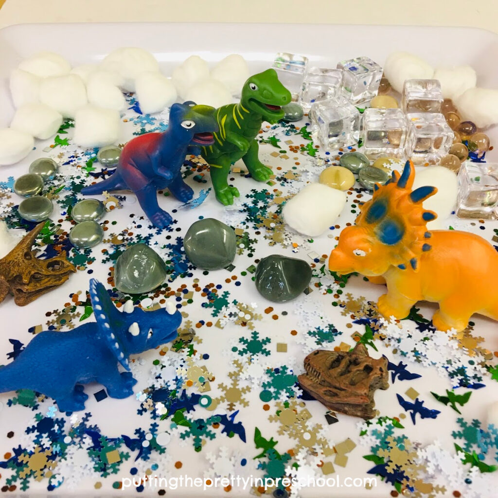 Polar dinosaur sensory tray with dinosaurs and winter-themed loose parts.
