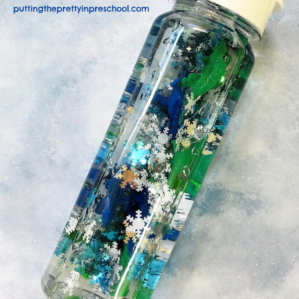 Polar dinosaur exploration sensory tube with snowflake confetti and miniature dinosaurs. An easy to prepare sensory experience for early learners.