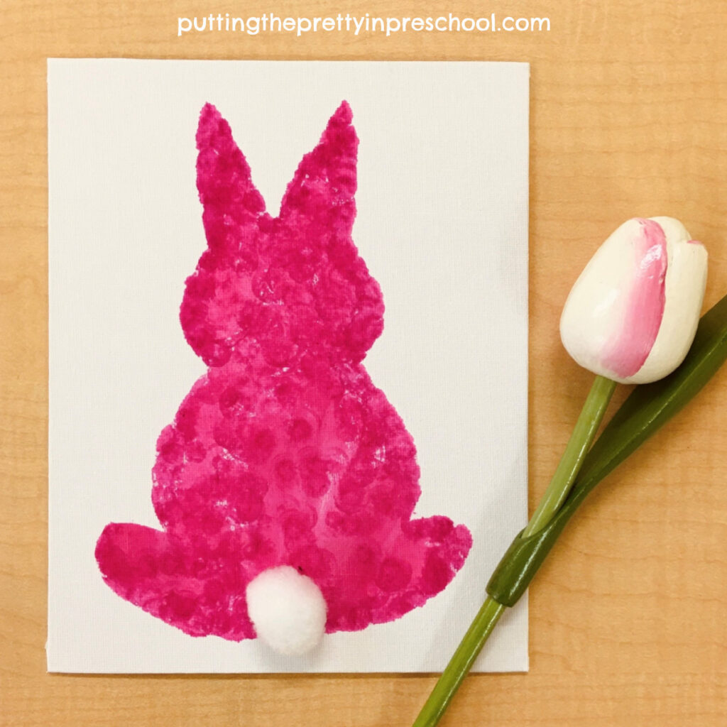 Pink silhouette bunny art made by dabbing dot markers on a canvas. This quick and showy art project displays well.