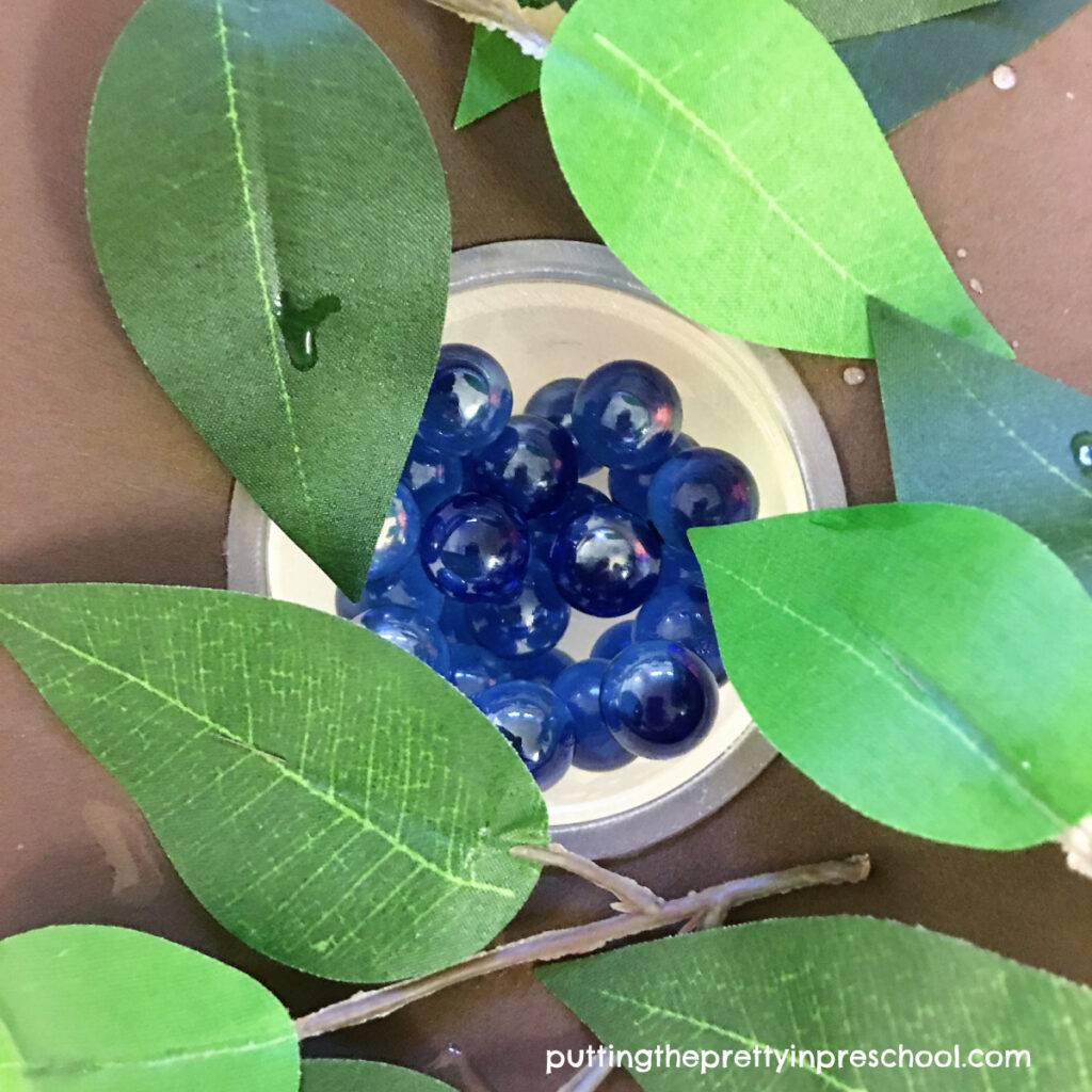 This turtle pond sensory bin includes a sunken nest with "eggs."