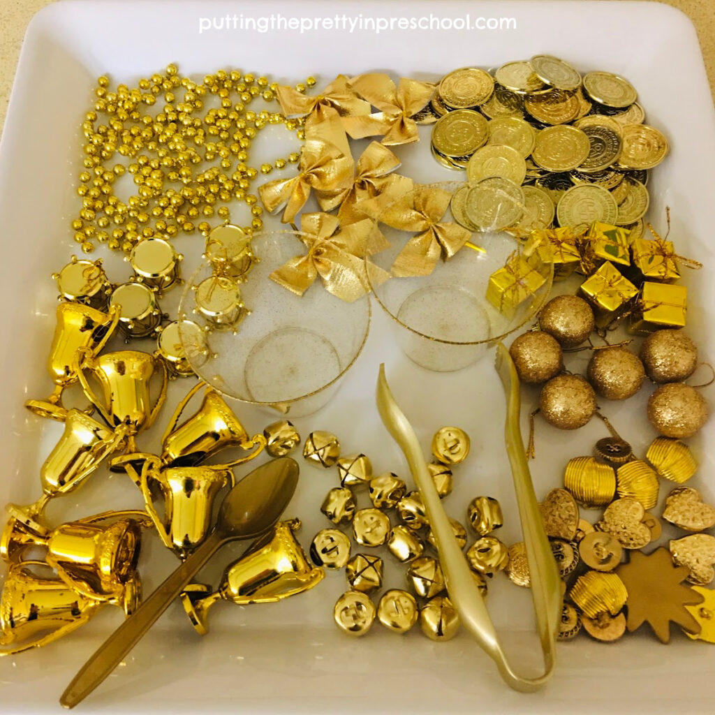 A sparkling New Year's all gold sensory tray filled with metallic items for little learners to explore.