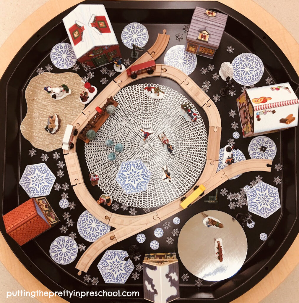 A winter-themed pioneer village tuff tray filled with people participating in outdoor winter activities during the Christmas season.