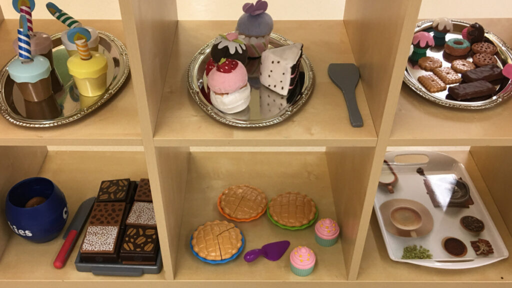 Delectable dessert bar play food displayed on a shelf with see-through cubicles.