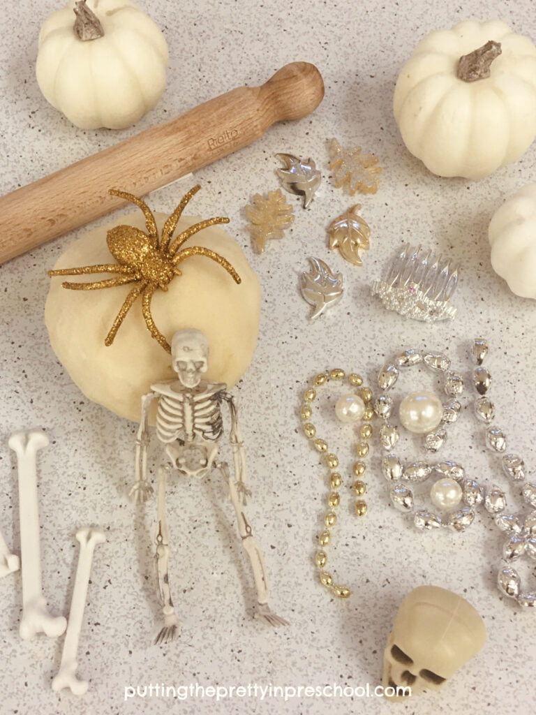 Silver and gold loose parts complement the neutral palette in this glam skeleton-themed playdough invitation.