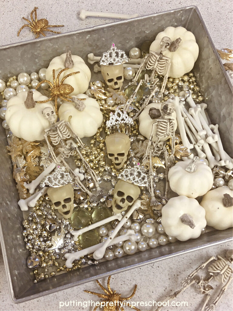 An easy-to-set-up glamourous sensory tub for early learners featuring skulls and skeletons, and gold and silver loose parts.