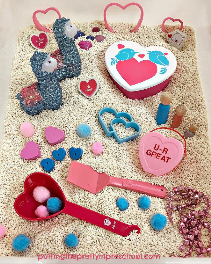 An adorable llama-inspired valentine sensory bin with a rice base. There are lots of fun heart-themed loose parts to explore in the bin.