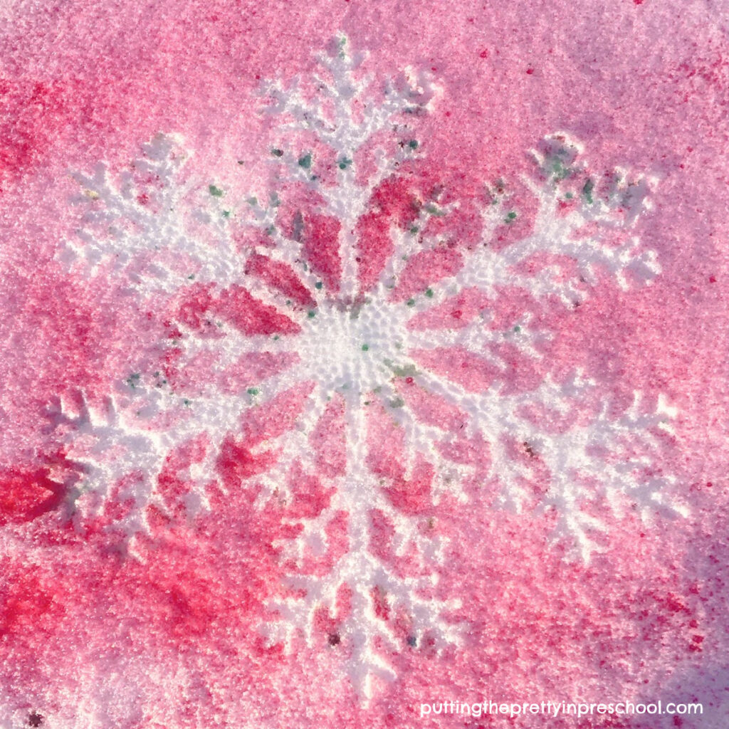 A beautiful red background snowflake silhouette created with a spray paint technique. A quick and easy ourdoor transient art activity.