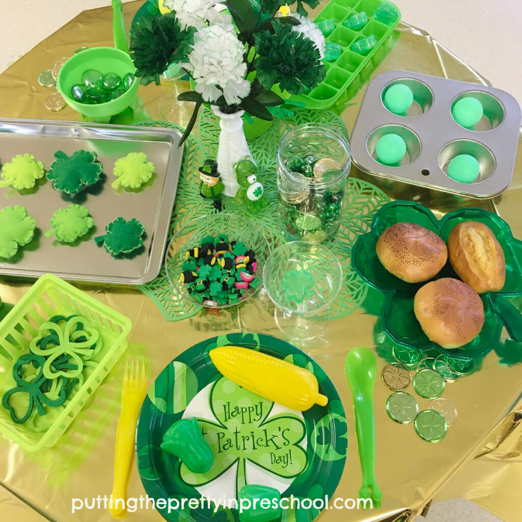 A green and gold St. Patrick's Day pretend play tablescape filled with themed play kitchen accessories to explore.