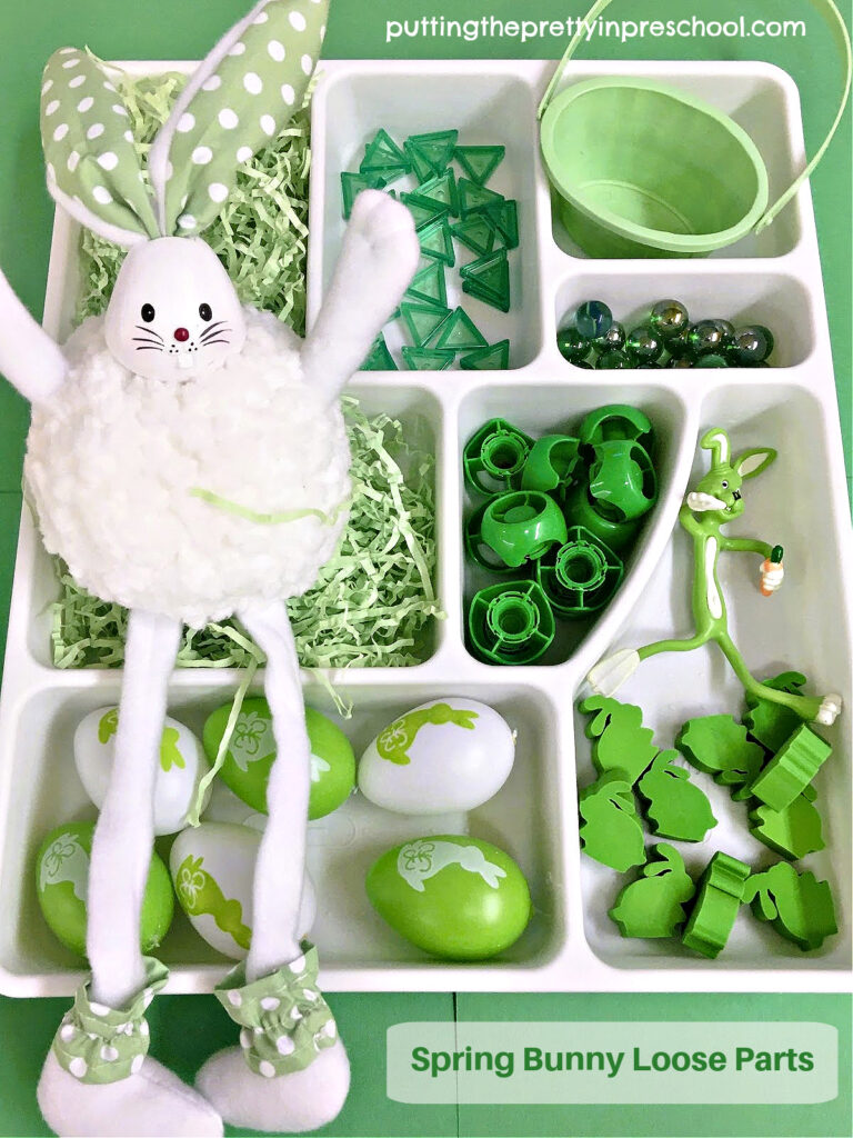 This spring bunny loose parts tray features green and white bunnies, eggs, and loose parts.