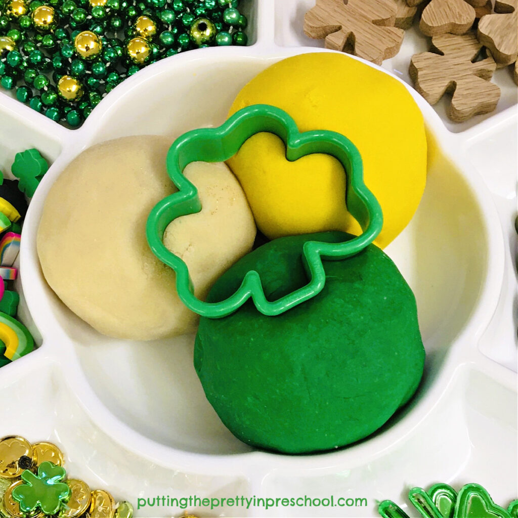Three different colors of playdough are featured in a St. Patrick's Day playdough tray for early learners to explore.