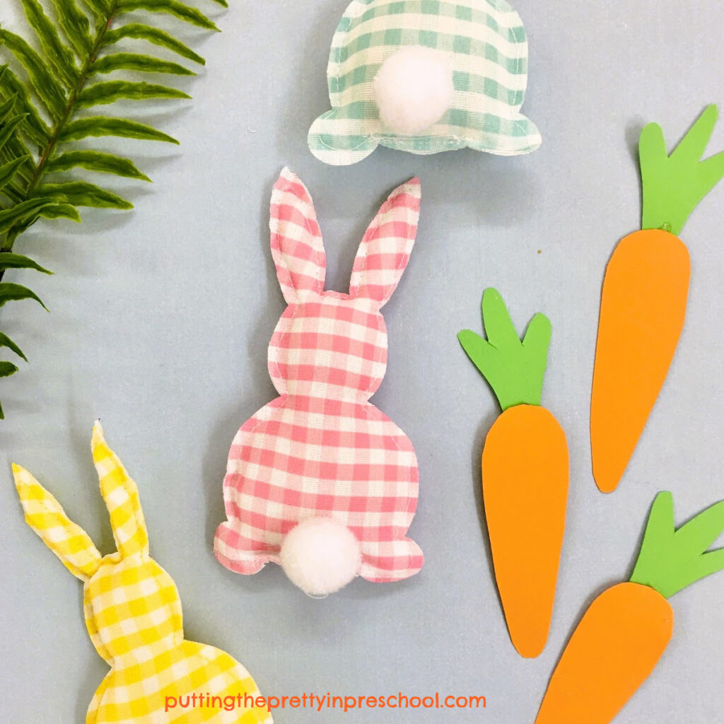 Stuffed bunnies cut from garland and paper carrots are highlights of a paper plate Easter basket craft that is sure to please.