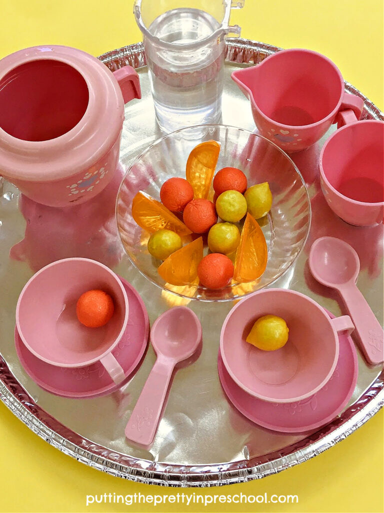Toy fruit counters add interest to this easy-to-set-up tea party water play sensory invitation for early learners.