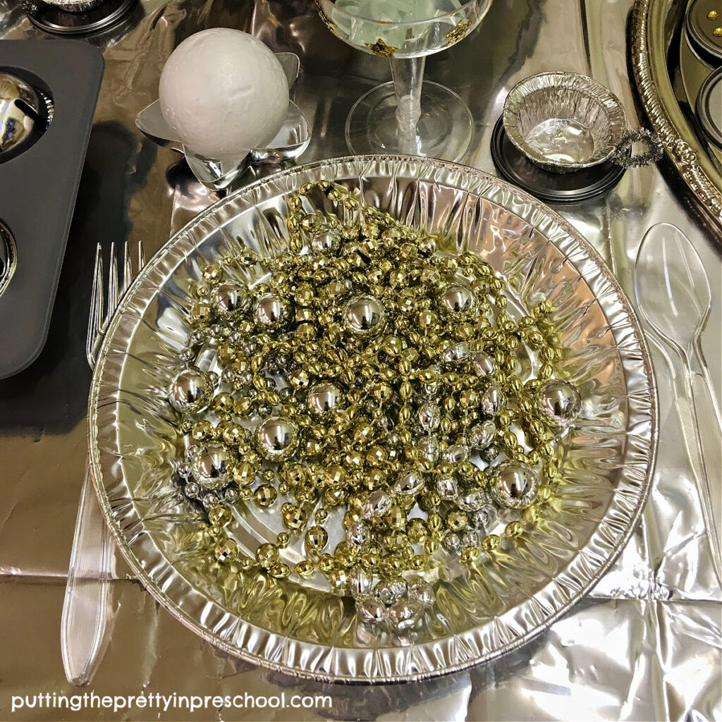 Cut metallic bead garland and necklaces make the perfect loose parts for an outer space spaghetti pretend play meal.