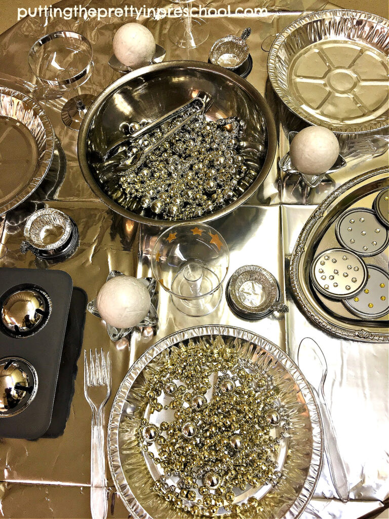 Shiny, metallic loose parts are the highlight of this outer space pretend play tablescape your little learners will love to explore.