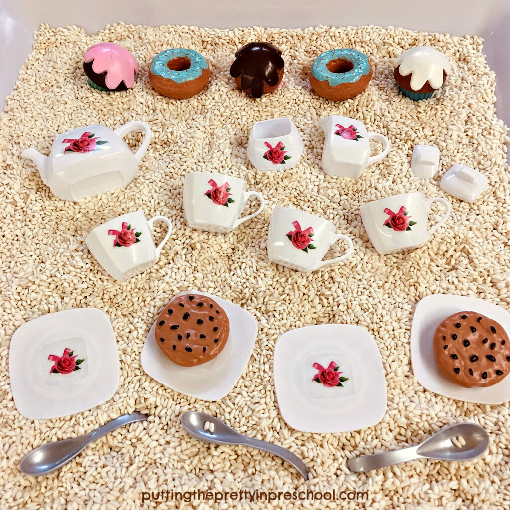 Dessert playfood and a miniature toy tea set are inviting to play with when set in a rice-based sensory bin.