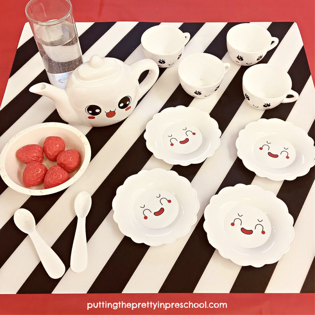 A black, red, and white theme sets the tone for a super inviting tea party water play sensory invitation.