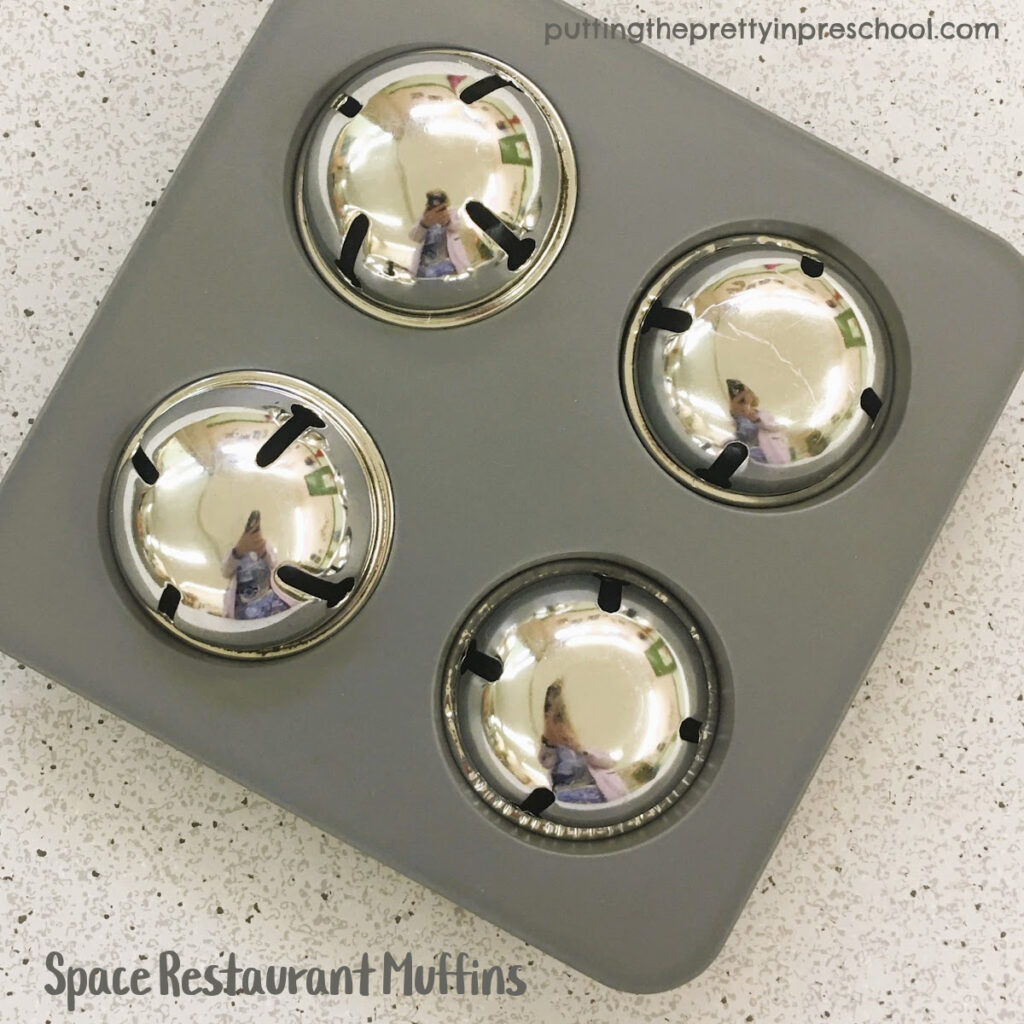 Large silver ingle bells are repurposed as muffins in a space restaurant dramatic play center.