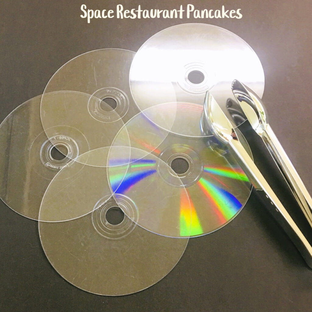 Clear discs are repurposed as pancakes in a space restaurant dramatic play center.