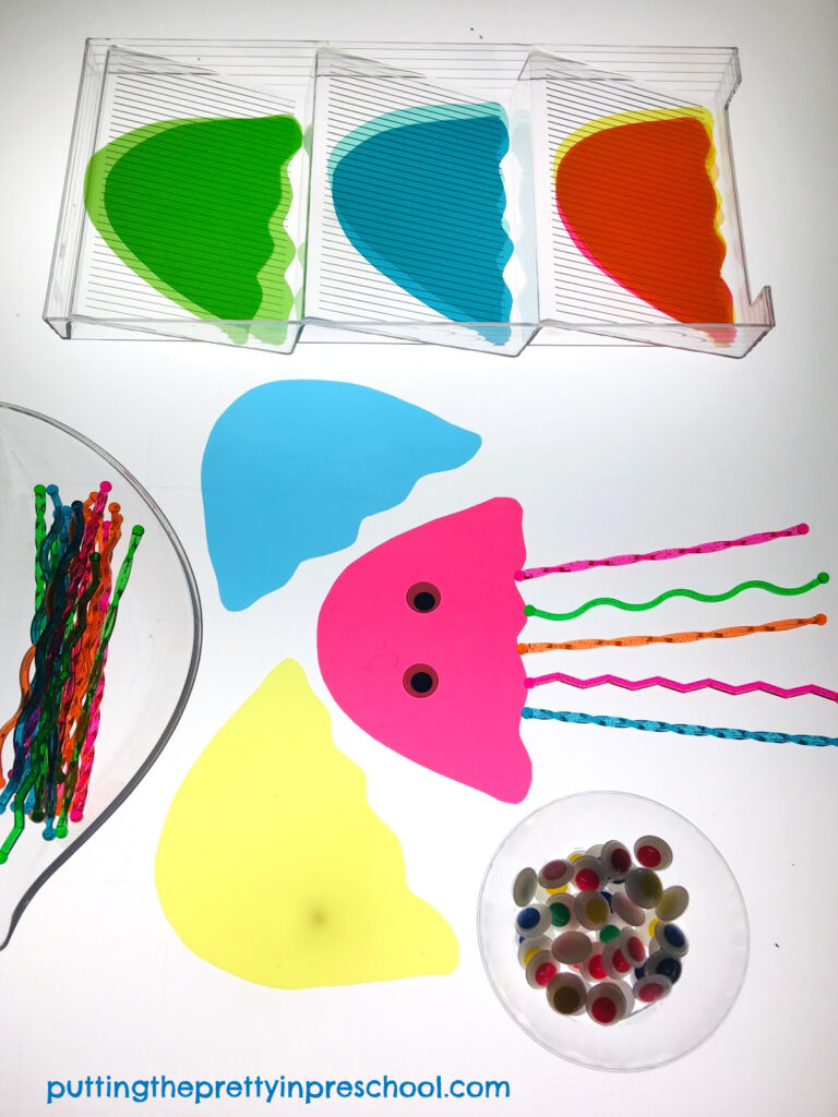 Invitation to create jellyfish on a light table with transparent stir sticks and page divider cut outs. Wiggly eyes are the finishing touch.