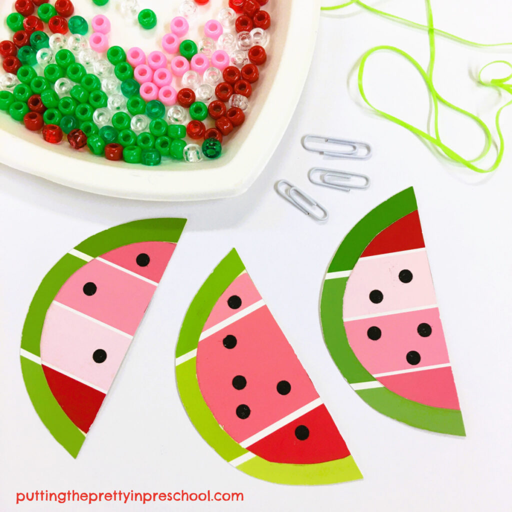 Supplies to make a beaded necklace with paint chip watermelon slices and green, red, pink, and clear pony beads.