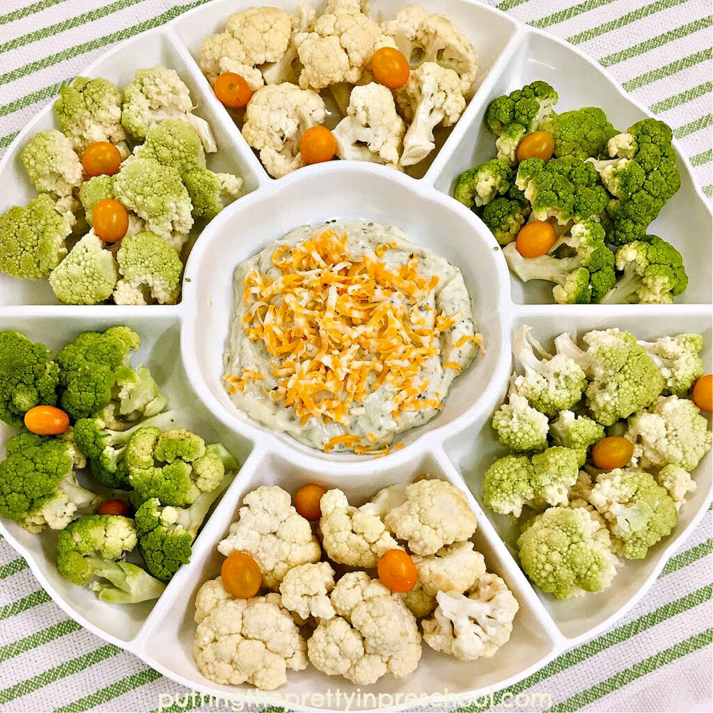 An eye-appealing vegetable tray with cream and green cauliflower and orange cherry tomatoes.