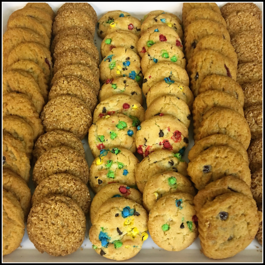 A cookie tray with rainbow, oatmeal, and chocolate chip cookies.