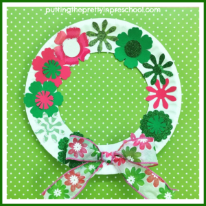 Paper plate spring wreath craft in pink and green colors. A low-cost art project suitable for all ages to do.