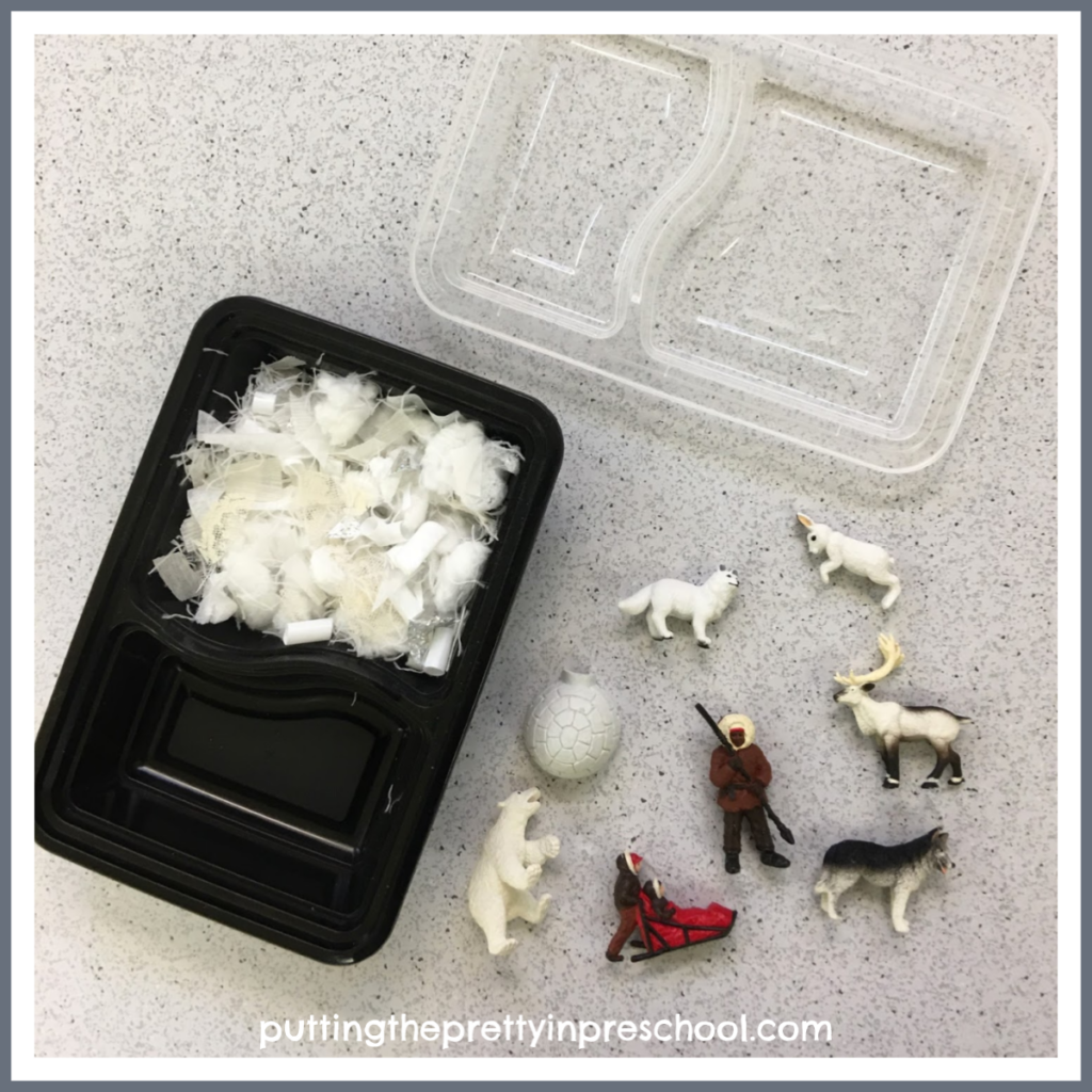 A snack tray repurposed as a small world with snipped craft supply snow and polar figurines. With the lid snapped on, this play tray is transportable.